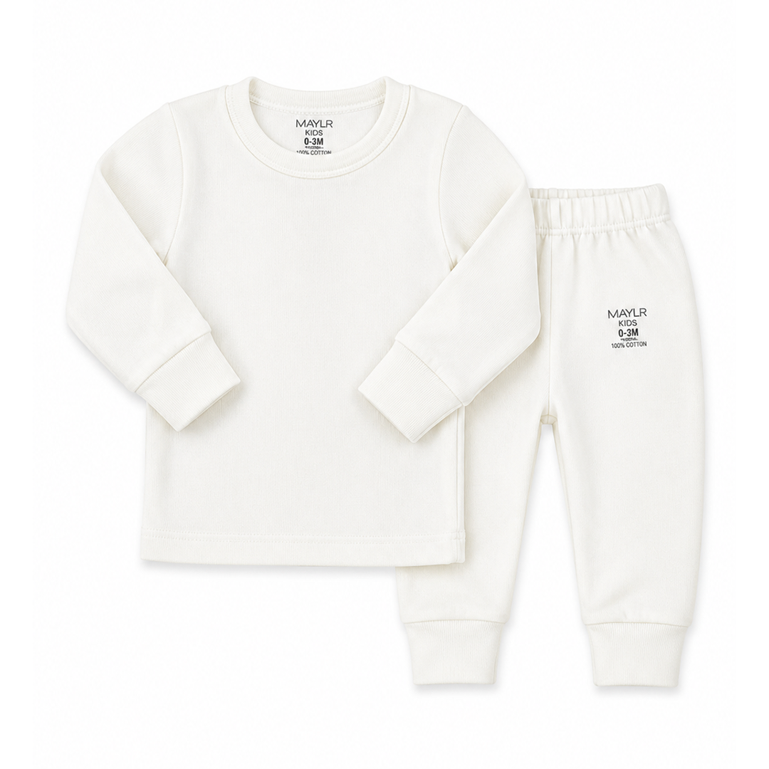 A two-piece baby loungewear set featuring a long-sleeve crewneck top and matching jogger pants in off-white. The top has a small black printed brand logo on the inside neck, and the pants feature a small black logo on the left thigh.
