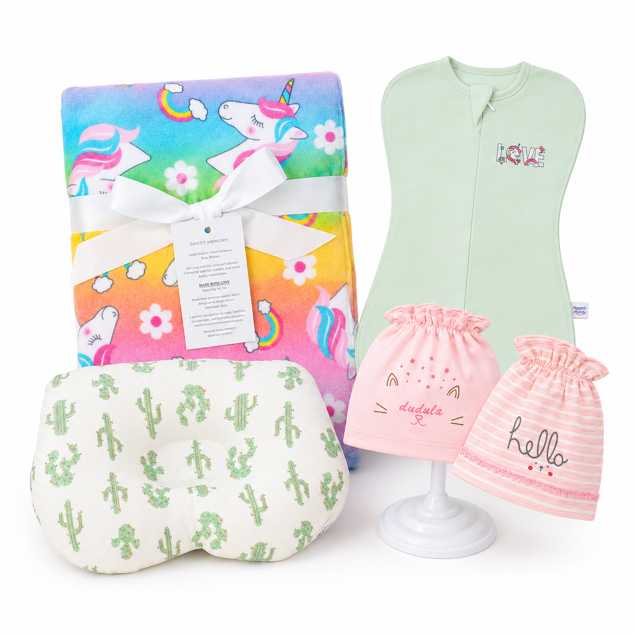 Baby gift set featuring a pastel unicorn blanket wrapped in a white ribbon, a mint green bib, a white pillow with green cactus prints, and two pink baby hats reading 'daddy' and 'hello' on a white background.