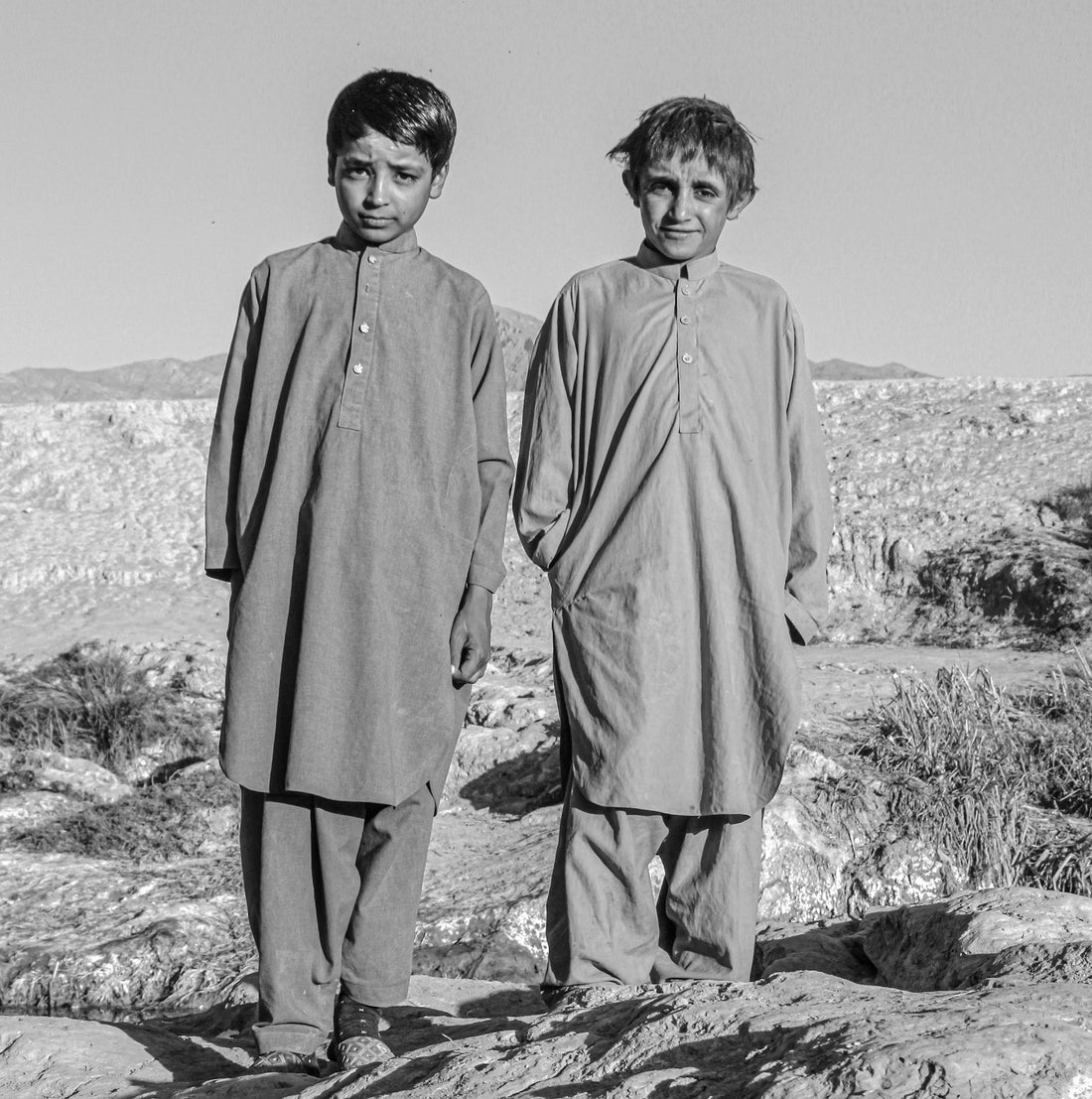 Two young boys in traditional shalwar kameez outdoors in Pakistan