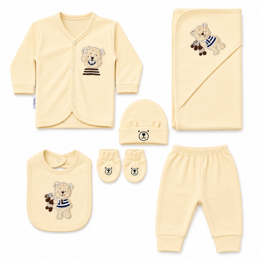 Baby clothing set with yellow outfit, hat, bib, gloves, and pants featuring teddy bear designs on a white background.