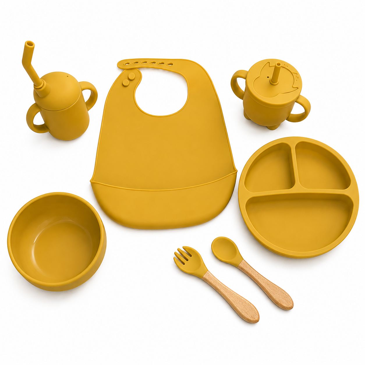 A baby feeding set in a warm mustard yellow color, including a silicone bib, divided plate, bowl, sippy cup, spoon, and fork, arranged neatly on a white background.
