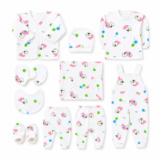 A baby clothing set laid out on a white background, including a long-sleeve top, footless onesie, pants, hat, bib, swaddle, and booties. The white garments are printed with a playful pattern of pink cartoon faces, green dots, and small black-and-white animal illustrations.