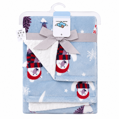 A folded baby blanket set in light blue fleece with a sherpa lining, decorated with cartoon snowman prints wearing red and black plaid scarves and white snowflake motifs. The set is packaged in a clear plastic hanger with a gray ribbon and bow, and a white paper tag.