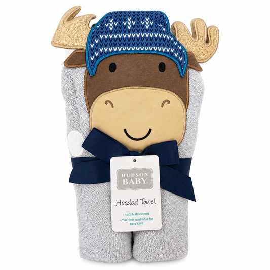 A plush baby towel shaped like a moose head, wrapped in a gray terry cloth body with a brown face, beige snout, blue knit hat, and navy scarf. A white product tag reading Hudson Baby is attached, on a plain white background.