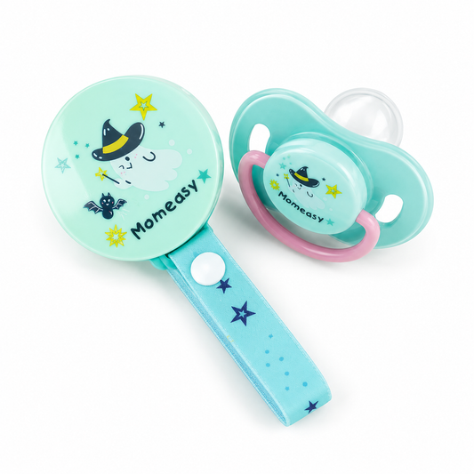 A baby pacifier and matching rattle set on a white background. The pacifier has a mint green shield with a pink ring, a clear nipple, and a witch graphic.