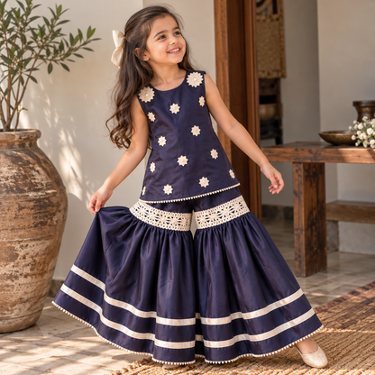 Child model wearing BabyCo navy blue sleeveless kurti and sharara set with ivory floral details and decorative lace bands
