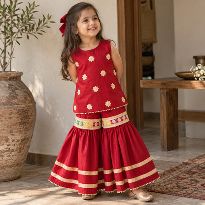Girl modelling BabyCo red sleeveless kurti and sharara set with ivory floral embroidery and gold border detailing