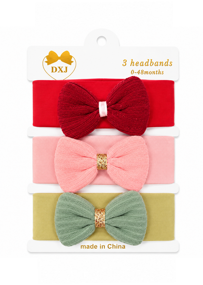 A package of three DXJ baby headbands for 0-48 months, featuring a red, pink, and sage green ribbed fabric bow design with gold glitter accents on a white backing card.