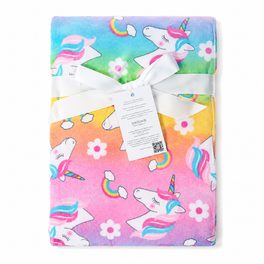 A folded plush blanket featuring a colorful unicorn print, wrapped with a white ribbon and a product tag, shown against a plain white background.